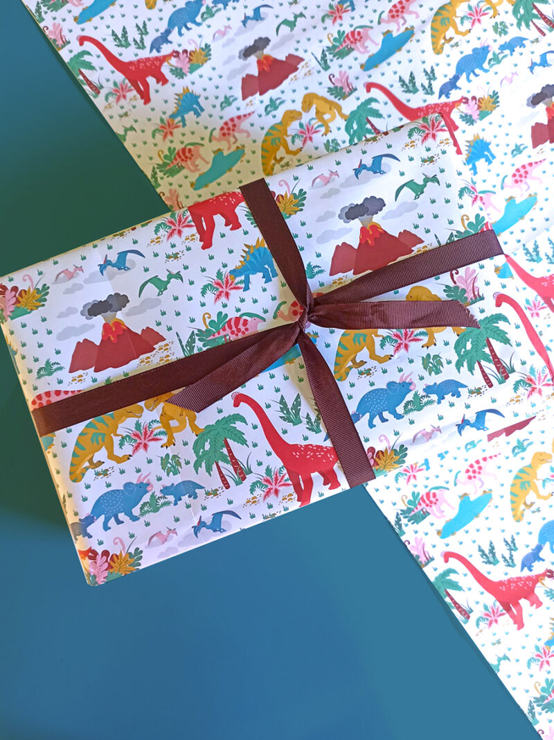 gift wrapped in illustrated dinosaur wrapping paper with brown ribbon and bow