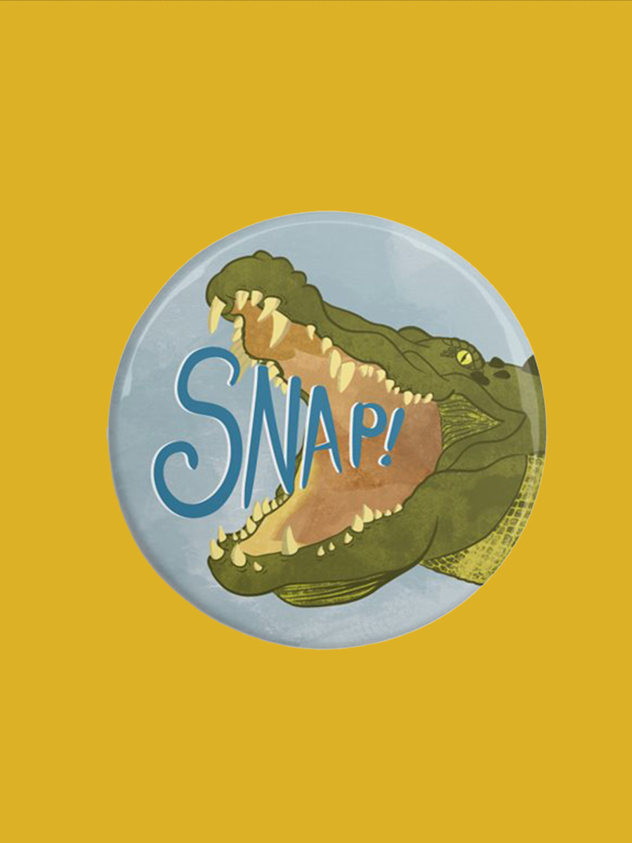 A round magnet with a crocodile open mouthed 'snap' illustrated by Min Dawson