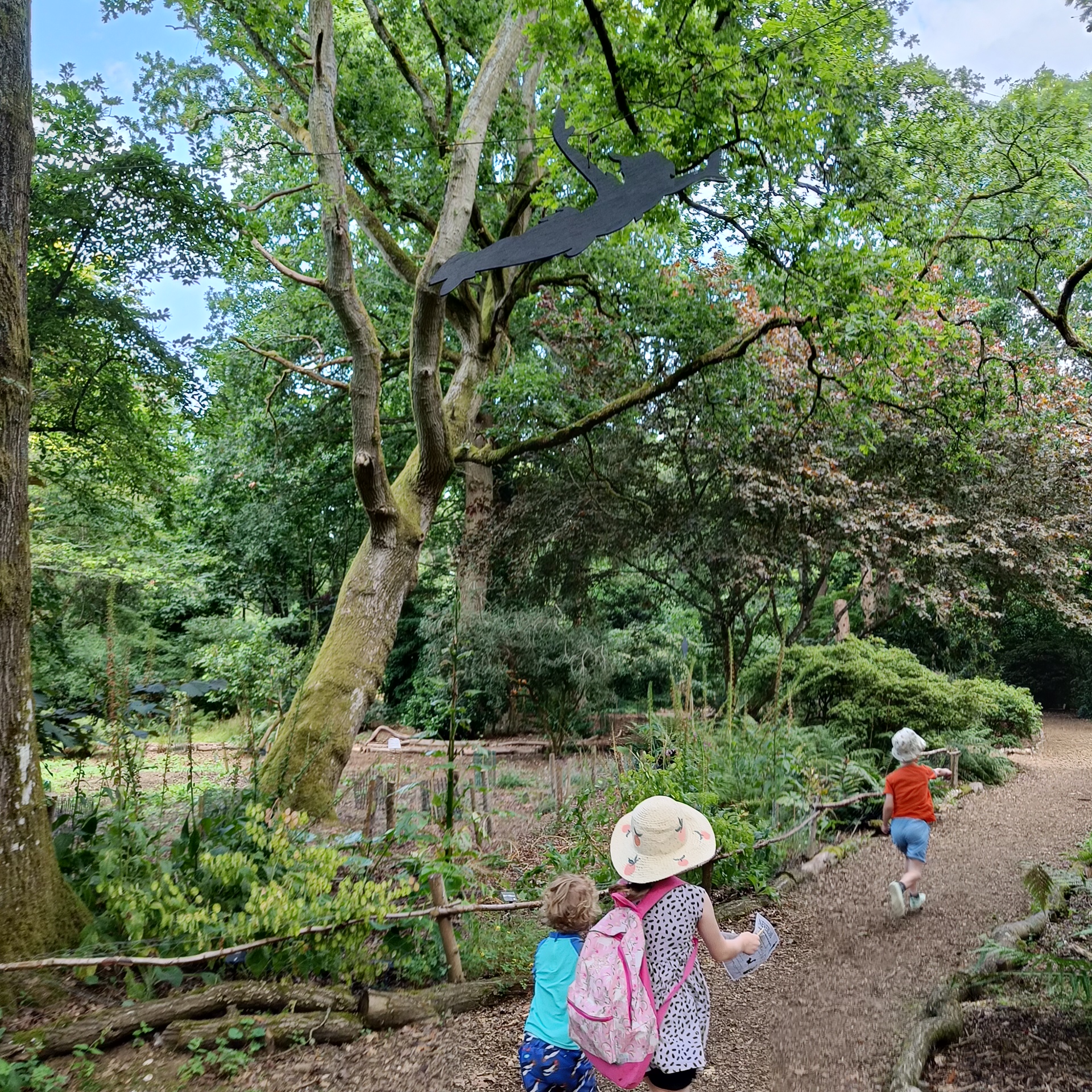 Children running through evenley wood garden with peter pan shadow overhead