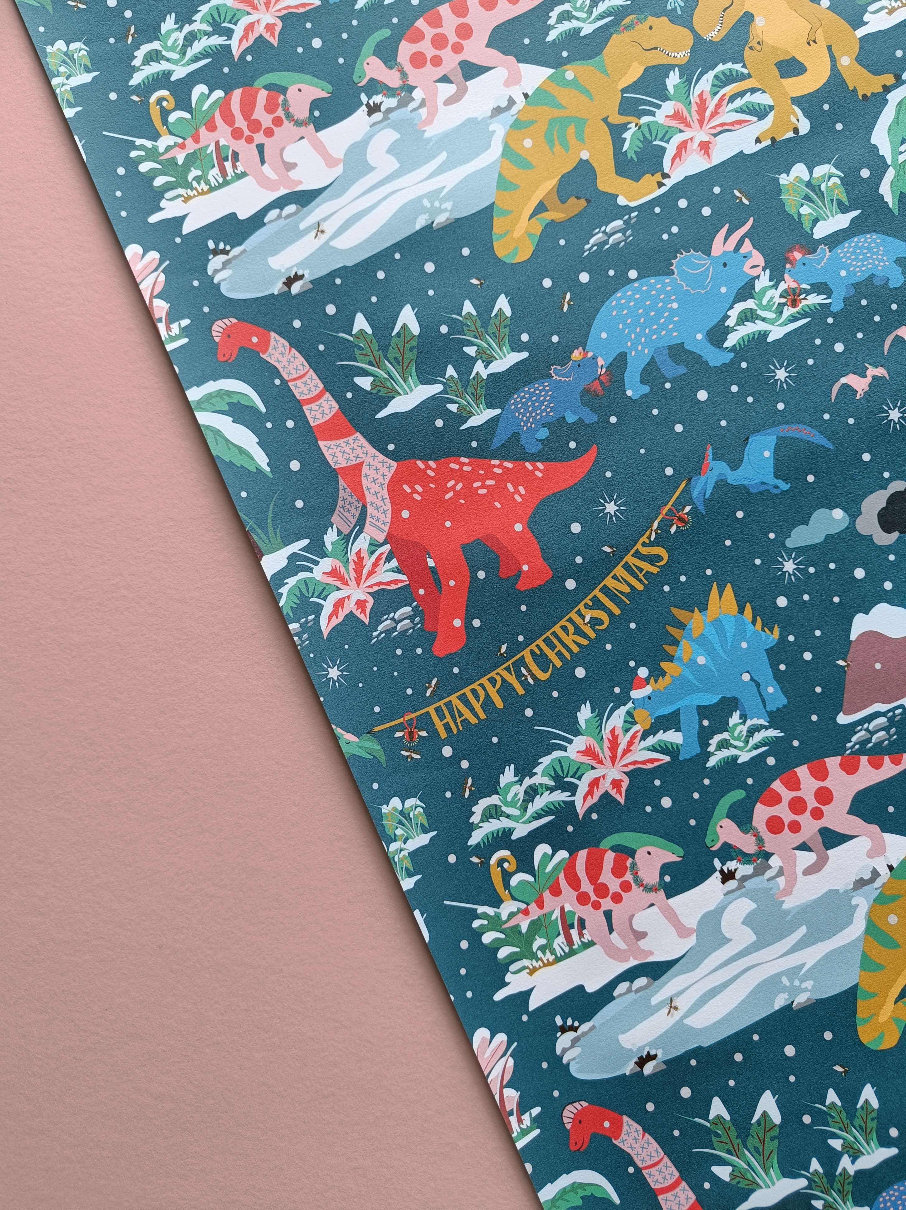 illustrated christmas dinosaur gift wrap sheet with brachiosaurus, triceratops, t-rex, stegosaurus and parasaurolophus dinosaurs getting ready for Christmas