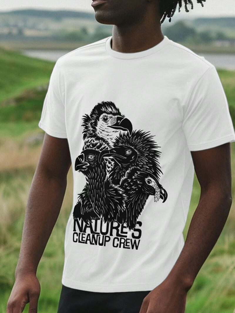Man stood in a field wearing a white coloured t-shirt with Curious Kin's Nature's clean up crew vulture species design printed on it