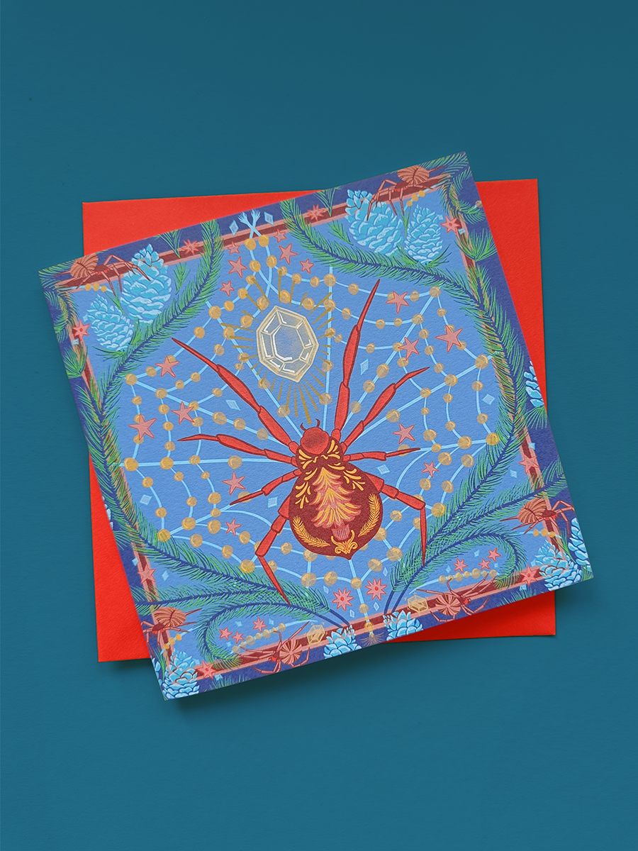 Illustrated Christmas Spider card with large jewel, large red spider and smaller spiders spinning webs of good fortune. Illustrated by min dawson.