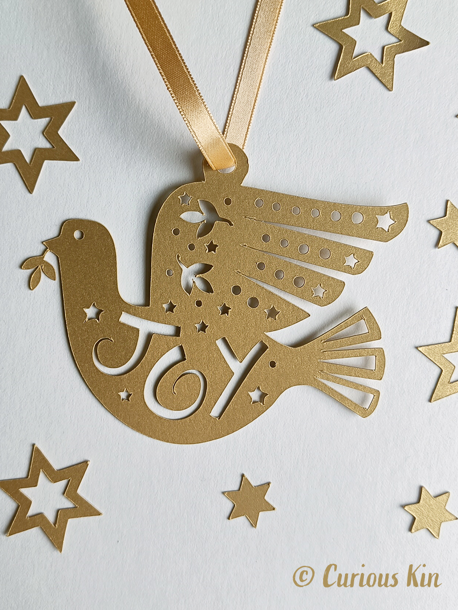 Frosted gold folk inspired paper cut Joy Dove and gold satin ribbon.