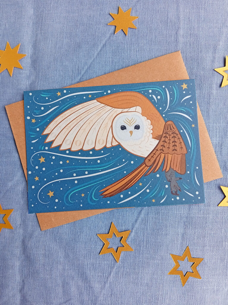 Greetings card with kraft envelope of a snowy winter scene with barn owl in flight surrounded by stars and swirls.