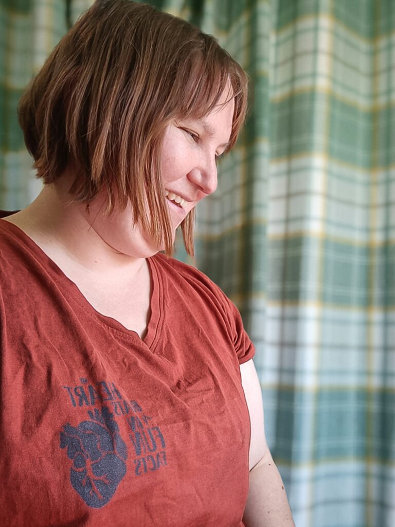 Photo of Min, Curious Kin founder, designer and illustrator wearing my heart beats in fun facts t-shirt smiling