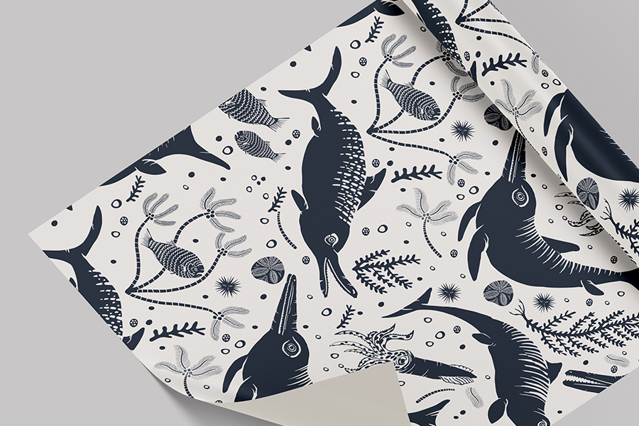 Wallpaper roll of Curious Kin's icthyosaur repeat pattern in cream and slate blue.