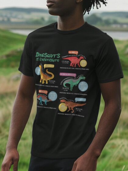 Man stood in field wearing a black t-shirt with Curious Kin's dinosaurs of Oxfordshire design
