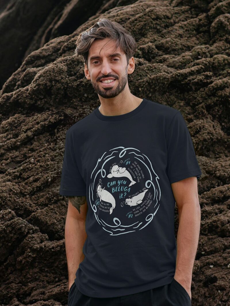 Man stood in front of rock face wearing Curious Kin's can you beluga it design printed on a navy t-shirt