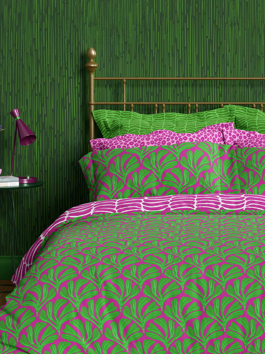 Curious Kin's neon fossils pattern collection showcased on bedding including abstract polka dot and striped pillow covers and ginkgo leaf bedding in magenta and green tones.