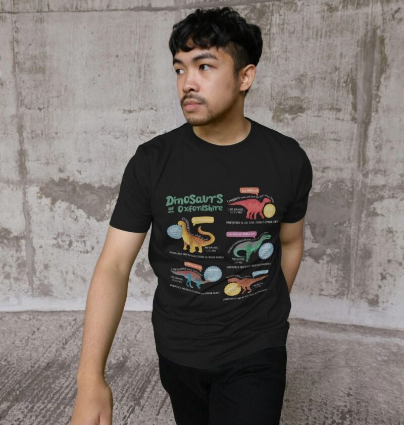 Man wearing a black t-shirt with curious kin's dinosaurs of oxfordshire design printed on it.