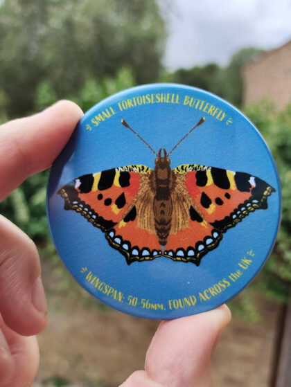 Hand holding a small tortoiseshell butterfly illustrated rectangular magnet by Curious Kin