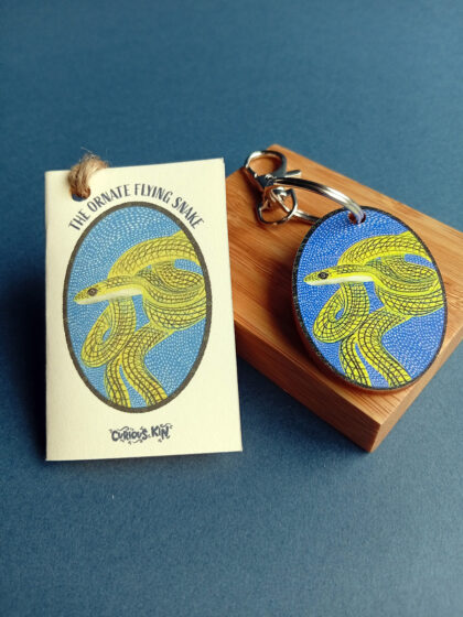 Ornate flying snake oval wooden keyring on wooden plinth with snake mini card and swivel clip.