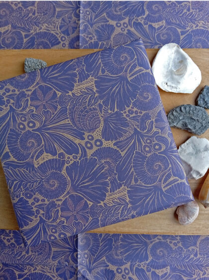 Gift wrapped in fossils paper designed by Curious Kin with biscuit ammonite, stones and shells.