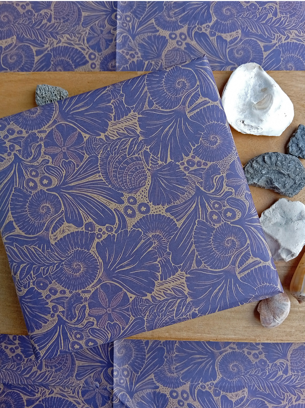Gift wrapped in fossils paper designed by Curious Kin with biscuit ammonite, stones and shells.