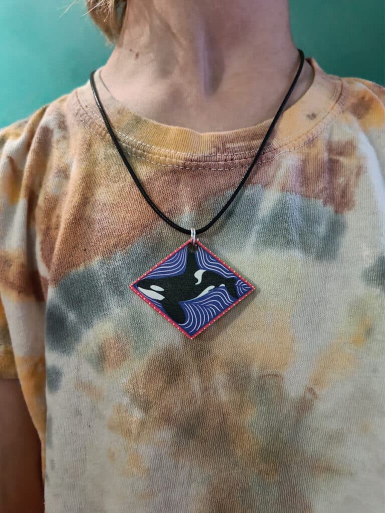 Child wearing tye-dye t-shirt and Curious Kin's orca necklace