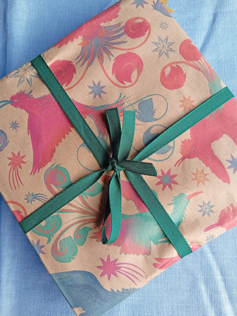 Gift wrapped in firebird eco wrapping paper and green tencel ribbon with bow. Paper illustrated by Min Dawson, Curious Kin