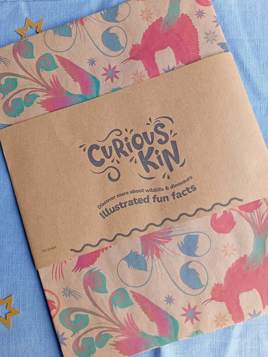 Firebird eco wrapping paper sheet with paper band featuring Curious Kin's logo.