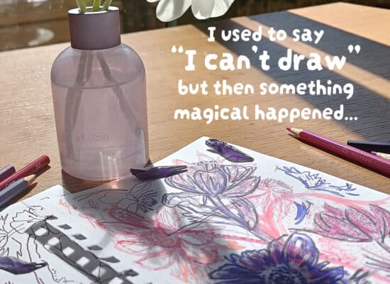 Table with anemones in purple vase with sketches of anemone flowers and pencils on table.