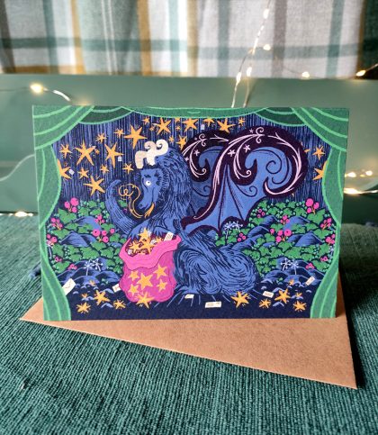 Card of the Christmas dragon with a bag full of star wishes in a cave with stars and ivy. With Kraft envelope.