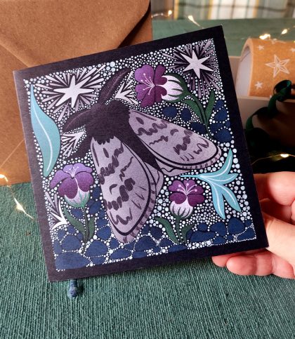 hand holding square card with Arctic woolly bear moth and stars card