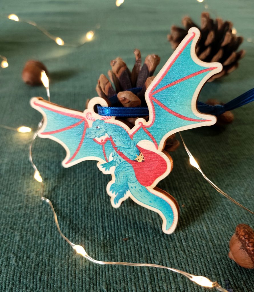 A wooden decoration with ribbon tie of a Christmas dragon with a bag full of stars