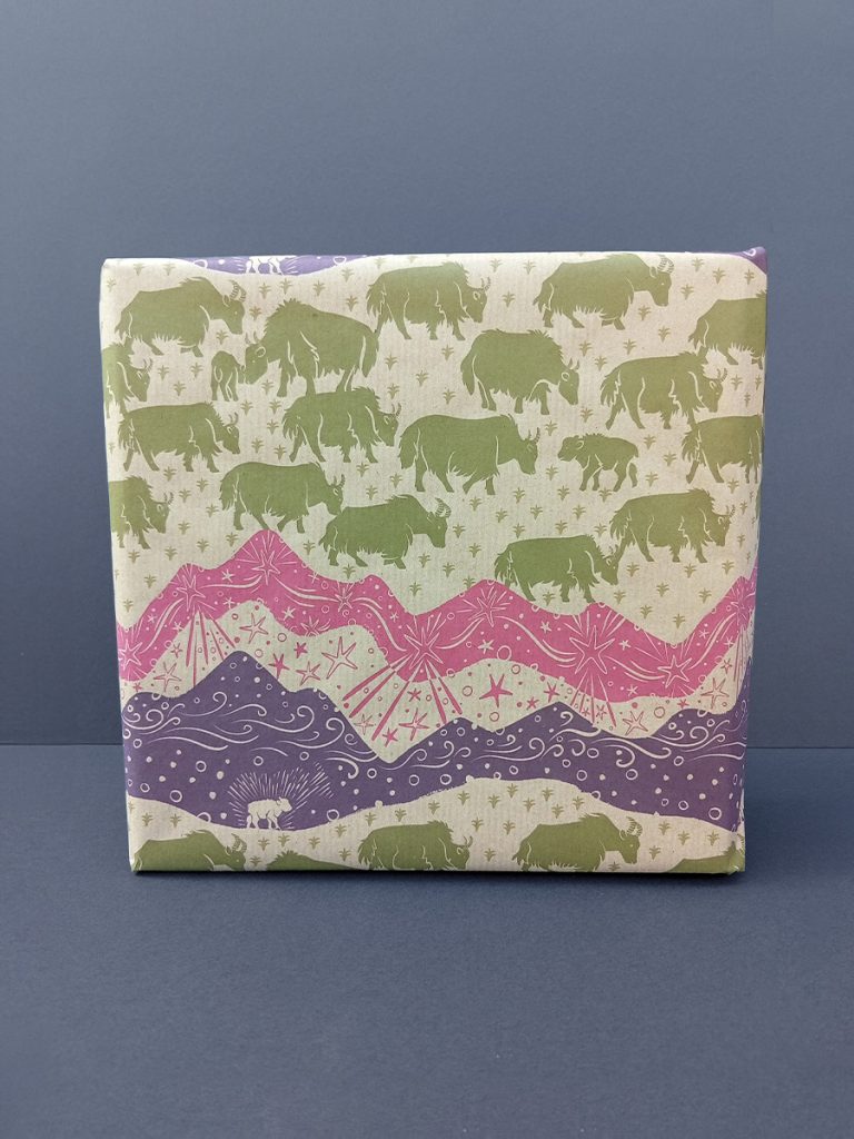 Gift wrapped in recycled wrapping paper with star mountain scape in pinks and purples and green himalayan yak herd. Hand-drawn.
