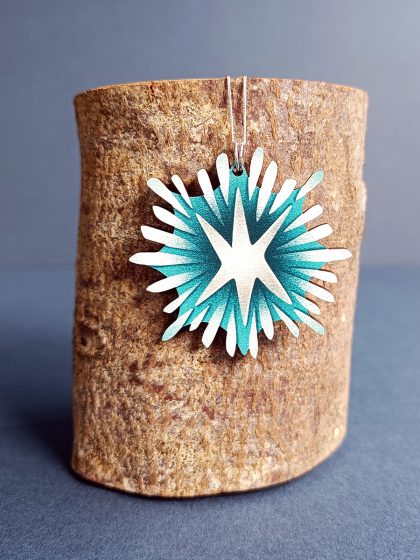 Starlight wooden shaped pendant hung on eco fine sterling silver chain hanging on a log
