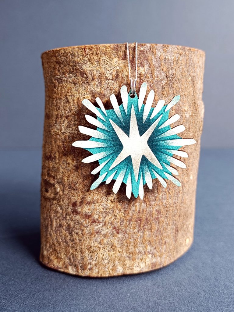Starlight wooden shaped pendant hung on eco fine sterling silver chain hanging on a log