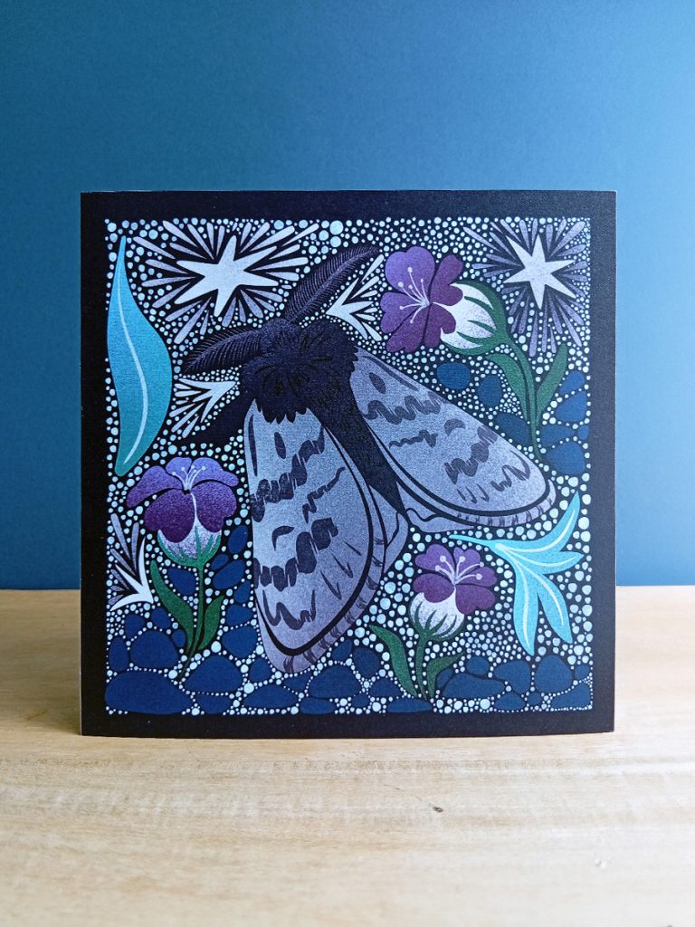 Square card with Arctic woolly bear moth illustrated in a linocut style in soft greys, purples and blues, surrounded by leaf litter and frosted stars.