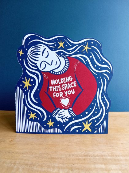 Holding space shaped card, illustration of woman with long hair and red jumper holding her hands with hair and stars tumbling around her and the words in hand-drawn font "holding space for you" with heart below.